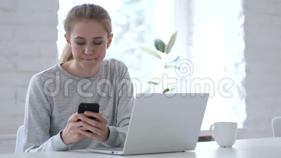 年轻女子在智能手机上浏览互联网视频的预览图