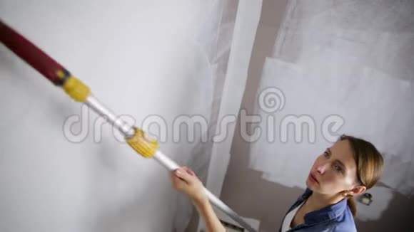 家庭改善美丽的女人用油漆滚筒画墙视频的预览图