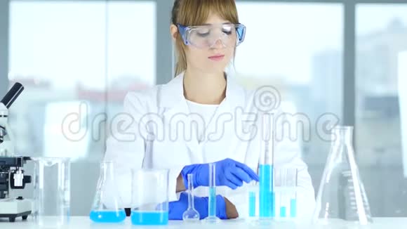 女科学家在实验室里研究试管中的蓝色溶液视频的预览图