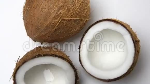 成熟的热带椰子和两半椰子在白色背景上旋转可循环的水果视频的预览图