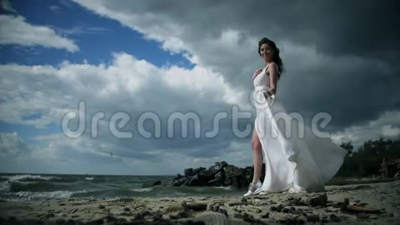 穿着白色连衣裙的漂亮女孩站在海滨视频的预览图