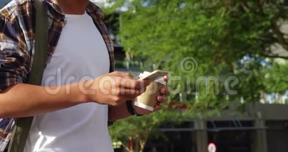 一个男人在智能手机上发短信拿着咖啡视频的预览图