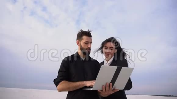 记者男女使用笔记本电脑在海岸准备报告视频的预览图