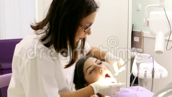 与一名年轻女性病人在牙科诊所工作的牙医视频的预览图