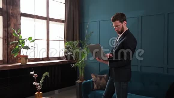 一位优雅的商人的肖像在豪华的蓝色办公室内部有笔记本电脑视频的预览图