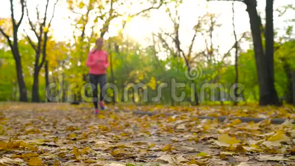 跑鞋日落时在秋天公园系鞋带的女人慢动作视频的预览图