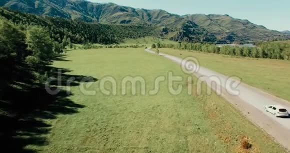 在山丘和草地上蜿蜒的道路上飞过汽车下面是农村公路视频的预览图