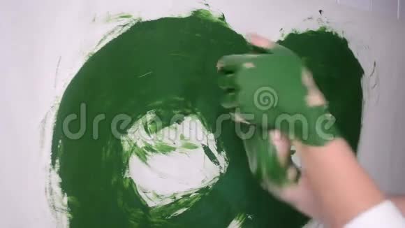 女孩把绿色的颜料涂在手上画在纸上视频的预览图