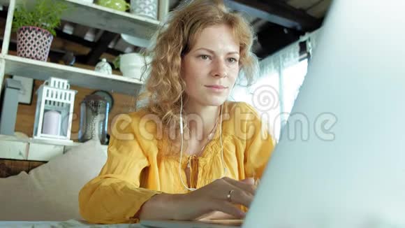 年轻女子带着现代笔记本电脑坐在咖啡馆里喝着咖啡卡布奇诺视频的预览图