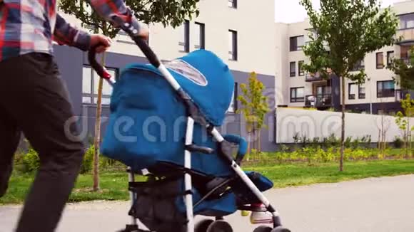 父亲带着婴儿在婴儿车里沿着城市散步视频的预览图