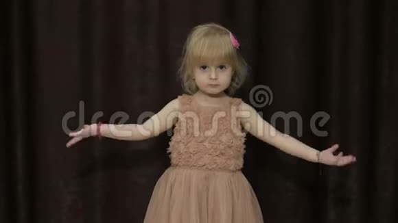 快乐的三岁女孩做脸跳舞可爱的金发孩子棕色的眼睛可爱的女孩微笑视频的预览图