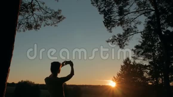 女士剪影与智能手机拍摄日落视频的预览图