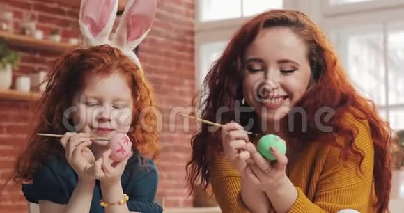 妈妈和她的小女儿正在准备复活节幸福的家庭在舒适的厨房里画复活节彩蛋视频的预览图