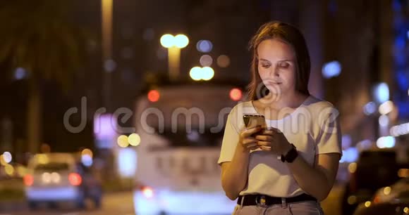 夜城背景下的一个年轻女孩看着智能手机屏幕视频的预览图