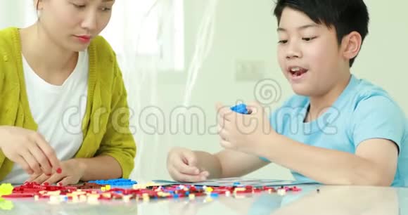 快乐的亚洲家庭母子一起玩塑料块视频的预览图