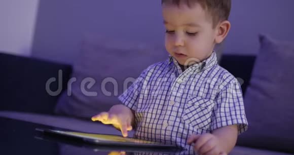 可爱的儿童娱乐与平板小男孩消磨闲暇时间玩手机游戏在光明中破碎视频的预览图