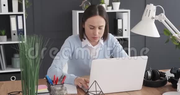 在办公室用笔记本电脑工作的女商人视频的预览图