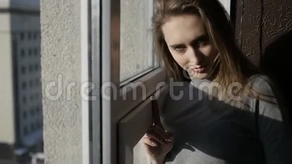 女孩在透过窗户看视频的预览图