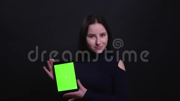 用平板电脑为年轻漂亮的黑发女性拍摄特写肖像并将绿色屏幕显示到背景相机上视频的预览图