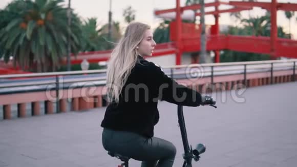 漂亮的金发女人在城市里驾驶电动自行车视频的预览图