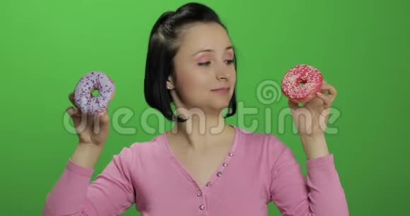 快乐美丽的女孩摆姿势玩甜甜圈铬键视频的预览图