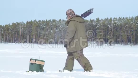 在冰冻的湖面上钓鱼的渔夫视频的预览图
