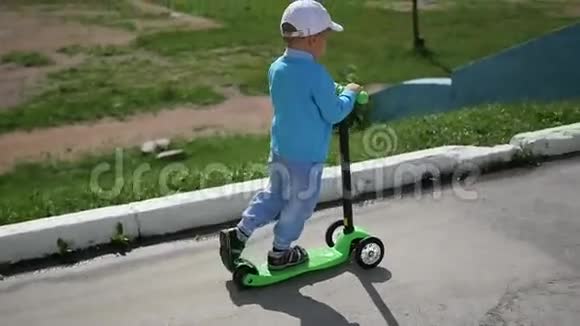 一个快乐的孩子在公园里骑着他的滑板车户外乐趣视频的预览图