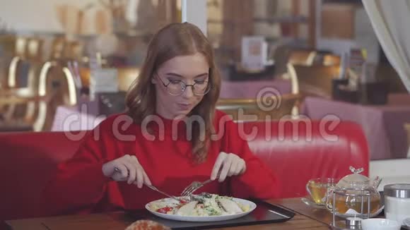 一位年轻女子坐在餐厅的餐桌前吃凯撒沙拉视频的预览图