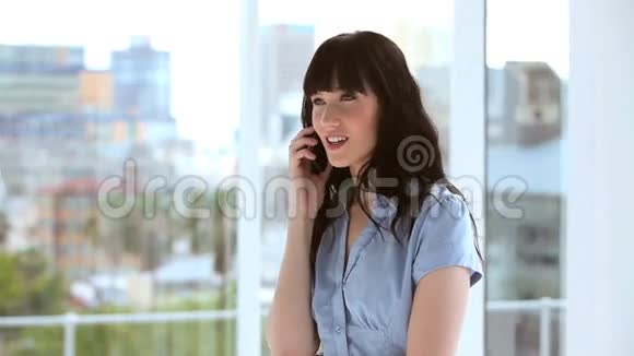 快乐的黑发女商人用她的手机视频的预览图