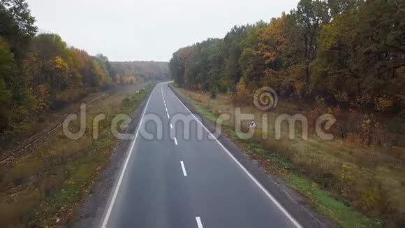 秋季森林环绕的道路上的汽车鸟瞰图视频的预览图