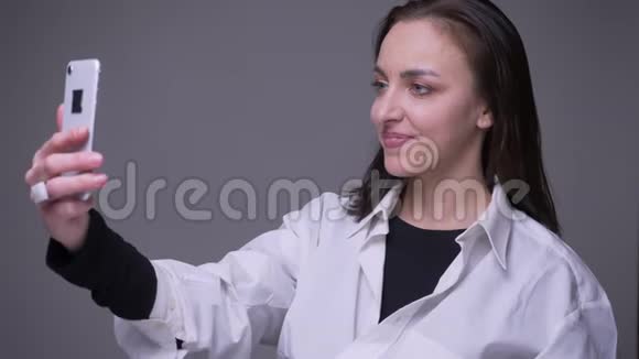 一位成年白种人女性的特写照片她在电话中打了个视频电话并带着背景微笑视频的预览图
