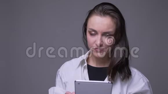 用平板电脑拍摄成年白种人女性的特写肖像并微笑着看背景镜头视频的预览图