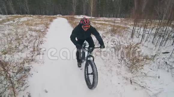 专业的极限运动员骑自行车在户外骑胖自行车骑自行车在冬天的雪林里男人是审判视频的预览图