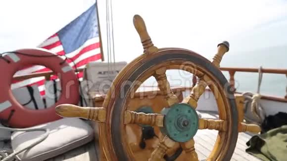 在阳光明媚的一天一艘木制古董帆船的方向盘和甲板在海洋中航行展示了木制部件和视频的预览图