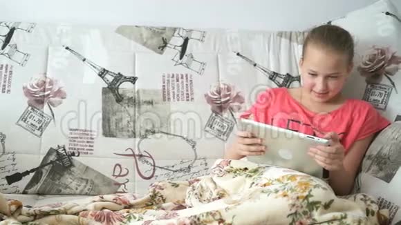 一个十几岁的女孩躺在床上拿着一台数码平板电脑视频的预览图