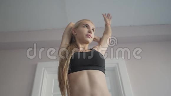 家庭健身年轻女子在训练前热身做伸展肌肉和关节的运动视频的预览图