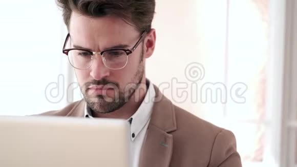 英俊的年轻商人在办公室里用笔记本电脑工作视频的预览图