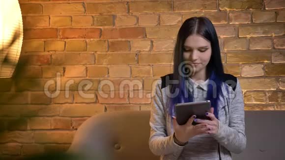 使用平板电脑拍摄年轻漂亮的白种人女性的特写肖像并在室内拍摄绿色屏幕视频的预览图