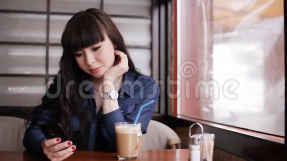 小女孩在咖啡馆里用智能手机视频的预览图