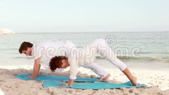 平静的情侣在海滩上伸展视频的预览图