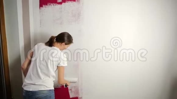 家庭改善美丽的女人用油漆滚筒画墙视频的预览图