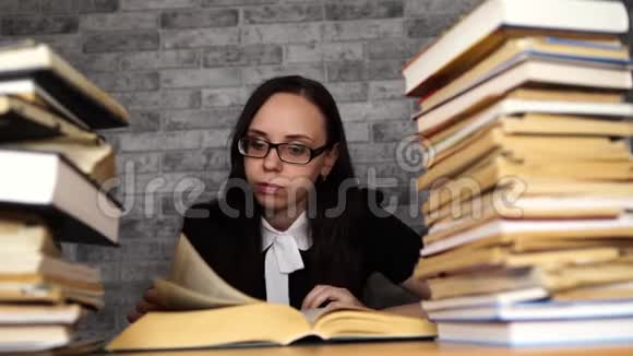 疲惫的女学生在书中读书一位身材魁梧的年轻女子坐在桌子旁手里拿着一堆书继续看书视频的预览图