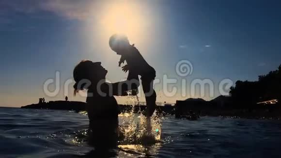 年轻的母亲把儿子抱在海边的怀里视频的预览图