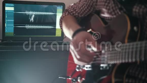 男音乐家用电脑作曲并录制弹吉他的配乐视频的预览图