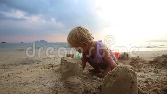 穿紫色泳装的女孩在沙滩上玩耍视频的预览图