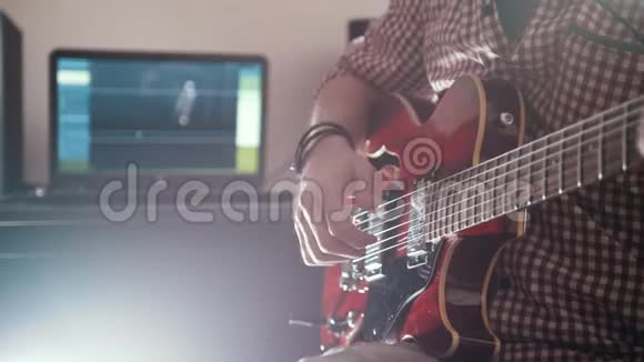 年轻的男音乐家用电脑作曲并录制弹吉他的配乐视频的预览图