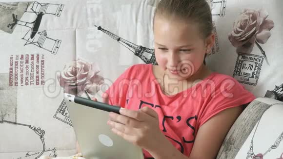 一个十几岁的女孩躺在床上拿着一台数码平板电脑视频的预览图