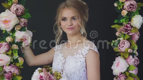 美丽的金发碧眼穿着一件白色的新娘礼服靠近一扇窗户放着一束鲜花视频的预览图