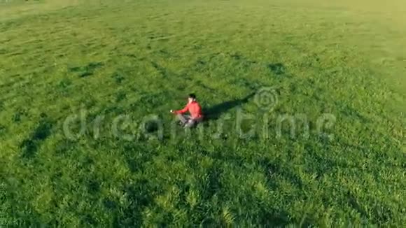 低空径向飞行超过运动瑜伽男子在完美的绿草在山上日落视频的预览图