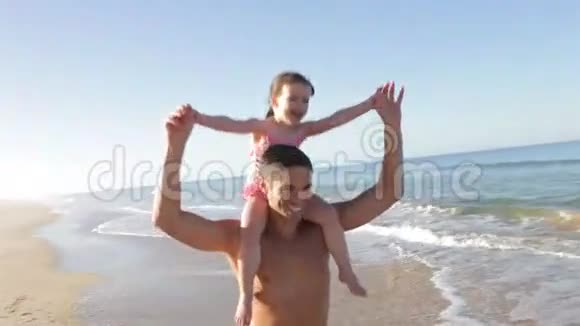 父亲带着女儿骑着肩膀沿着海滩奔跑视频的预览图